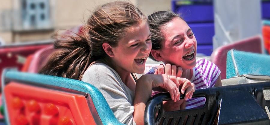 two girls laughing while riding on scrambler carnival ride