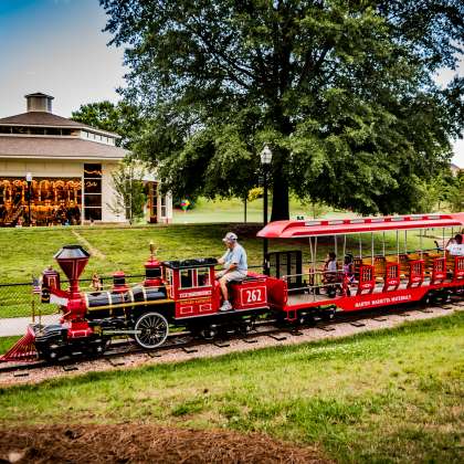 Red train ride moving through Village Park