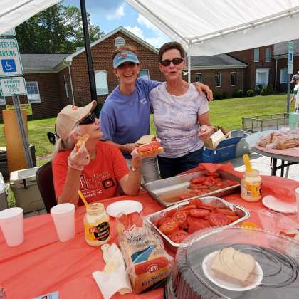 Three women under tent making tomato sandwiches