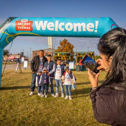 Woman taking picture of family under Day Out with Thomas welcome sign