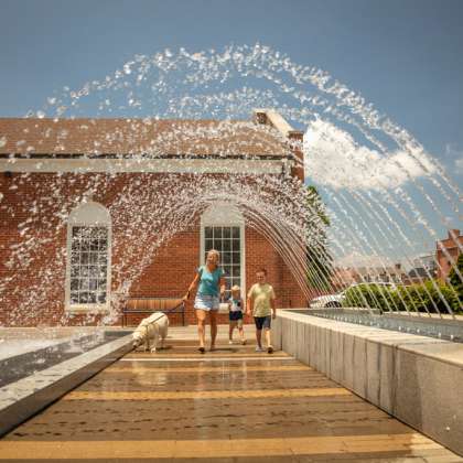 Family and dog walking under water feature in Downtown Kannapolis