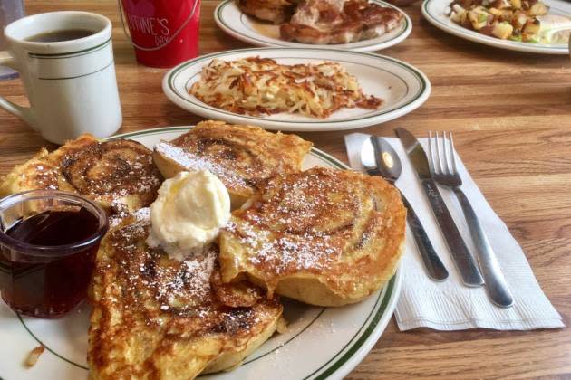 Plate with French toast, butter and syrup on table next to coffee cup