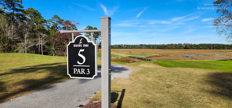 view of a golf course hole with marshland in the background
