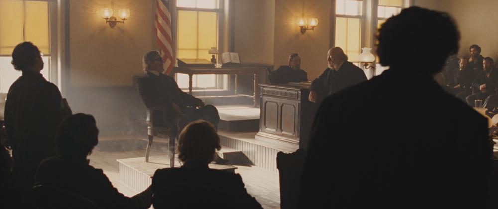 True Grit screengrab showing the dusty interior of a Courthouse with silhouetted figures