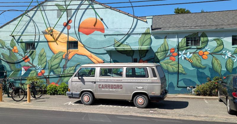 Mural on side of Open Eye Cafe showing coffee bean plants, a bird and sun