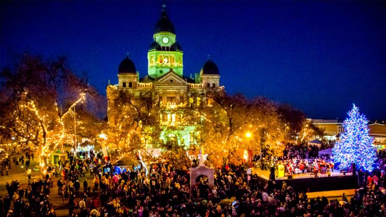large crowd at night surrounding a lit courthouse and christmas tree