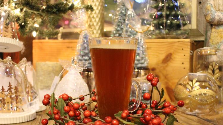 glass of wassail on a table surrounded by christmas decorations