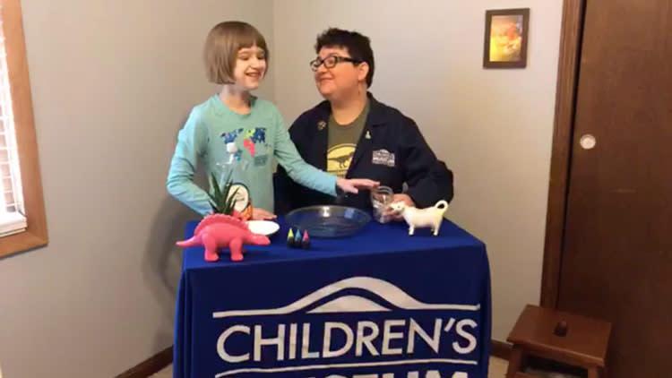 Mother and Daughter Working on science experiments at a table with banner reading "The Children's Museum of Indianapolis"