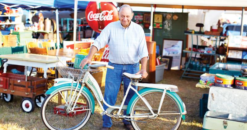 Man posing for a picture with an old bike during the Liberty Antiques Festival in Liberty, NC