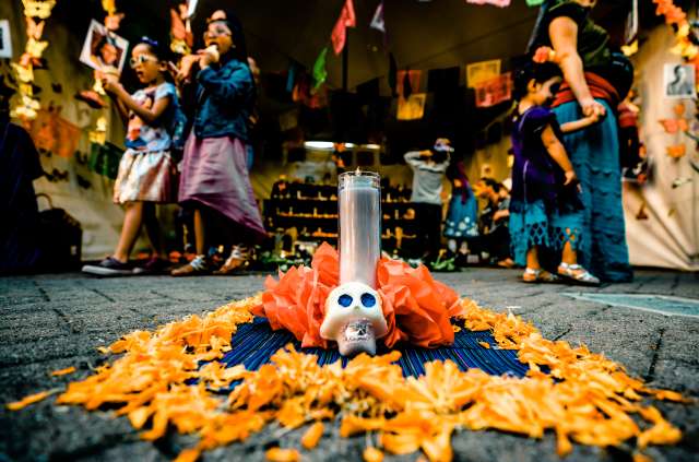 Dia De Los Muertos shrine and festival goers in Oakland CA