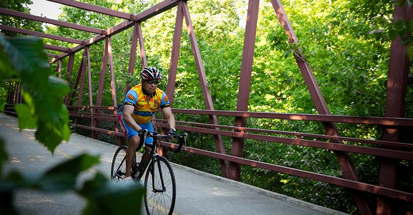 A male cyclist rides on a paved path in Busse Woods