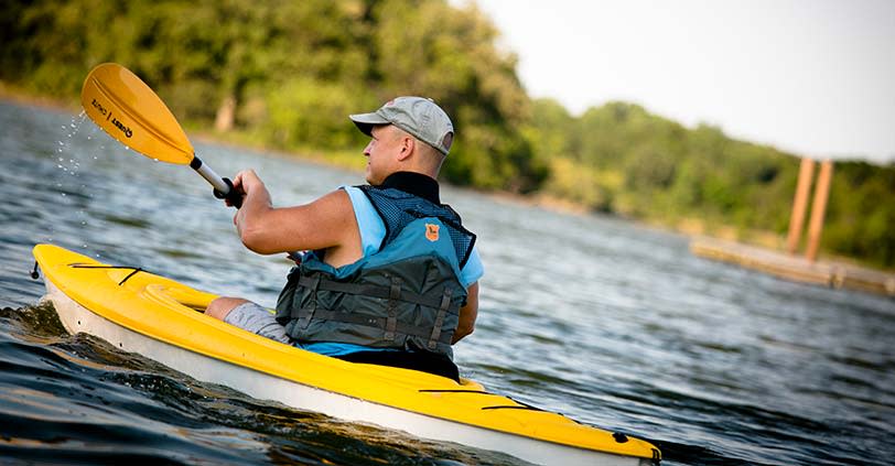 A man in yellow kyack paddles across a lake in Busse Woods