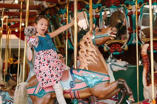 Child riding a horse on the carousel.