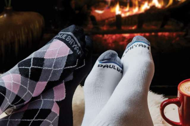 Two people wearing socks in front of fireplace.