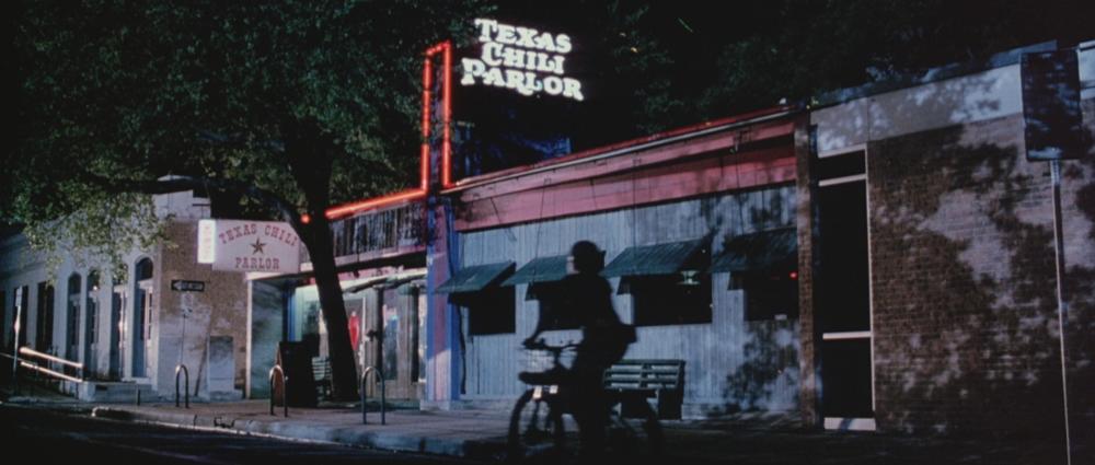 Grindhouse screengrab showing the exterior of a bar with a neon sign reading Texas Chili Parlor