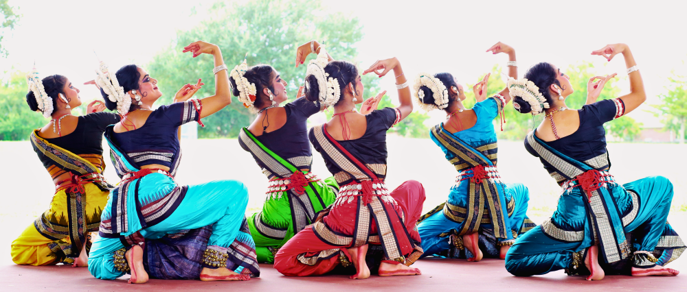 Indian dancers dancing in unison on an outdoor stage,