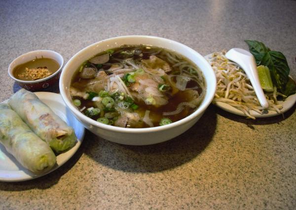 Two spring rolls with peanut dipping sauce are paired alongside a bowl of pork pho at Green Papaya Fort Smith, Arkansas.