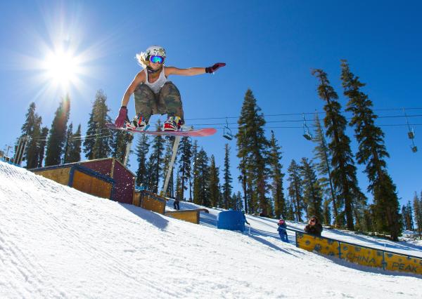Sun beams in the sky, as snowboarder soars through the air