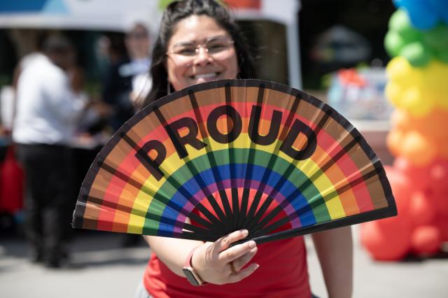 Girl with rainbow fan that says proud