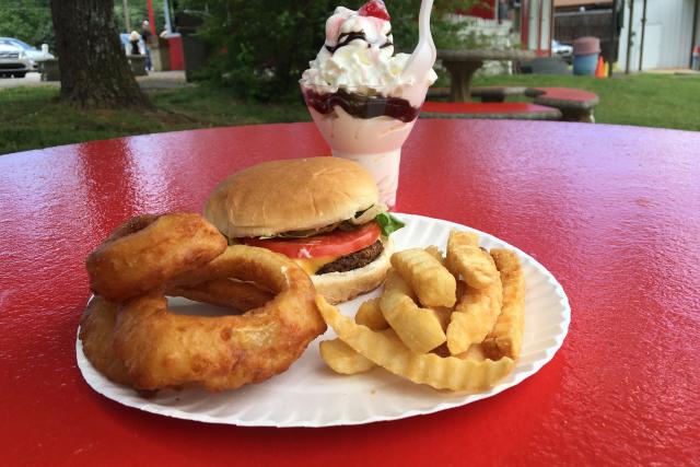 A local joint serves up a cheeseburger with onion rings & crinkle-cut fries and an ice cream sundae.