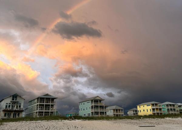 storm clouds and a rainbow build as the backdrop behind vacation rental homes on Cape San Blas.