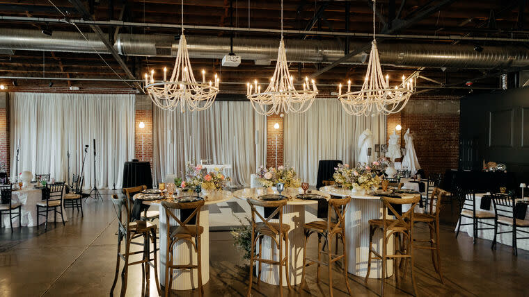Chandeliers are lit above a table set up for a wedding reception by Le Luci Lighting.