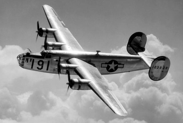 A Consolidated B-24 Liberator glistens in the sun at high altitude in the clouds.