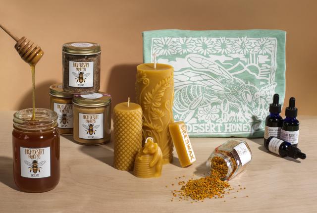 High Desert Honey Co. products including raw honey, wellness tinctures, beeswax candles, and a bee-themed t-shirt on display.