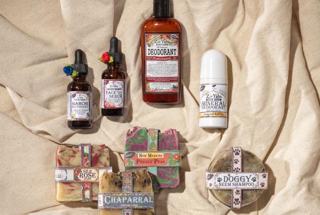 A collection of skincare products on beige fabric includes serums, deodorants, and soaps with colorful labels.