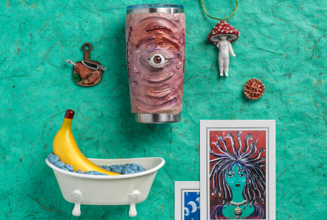 Collection of quirky art objects on a turquoise background, including a sculpted tumbler with a single eye, a banana in a tiny tub, a mushroom figurine, and a Medusa illustration.