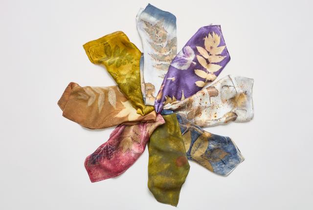 Silk scarves in purple, blue, green, gold, and pink display leaf patterns, arranged in a circle on a white background.