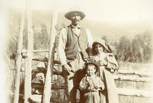 A man and his children stand near a Mora Valley fence in 1895.