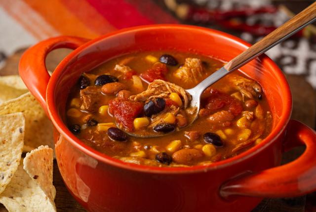 Close-up of a bowl of chicken taco soup with tortilla chips.