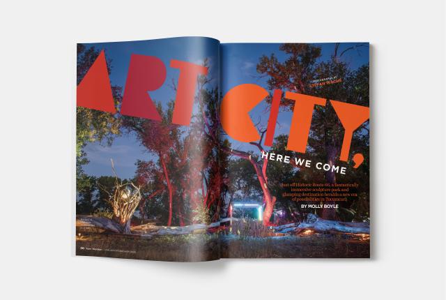 Magazine spread with large “Art City” title over a nighttime scene of illuminated trees and outdoor sculptures.