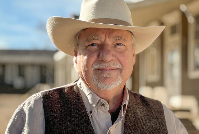 Portrait of historian and author Paul Andrew Hutton wearing a beige cowboy hat and brown vest outdoors.