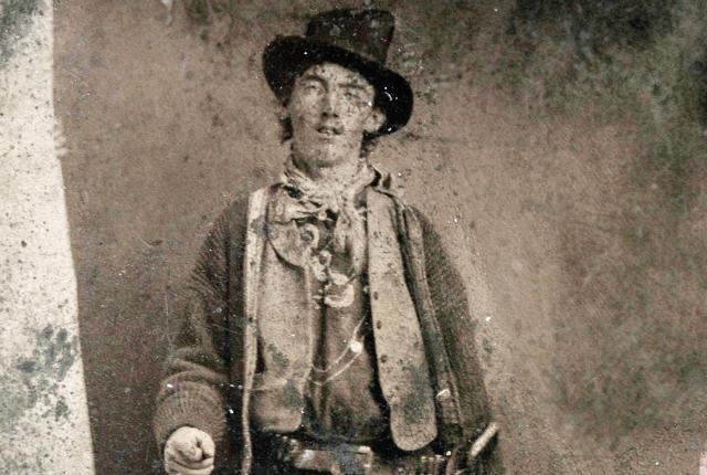 Bill the Kid poses for a ferro-type photo outside a Fort Sumner saloon in 1879 with a Winchester carbine and Colt revolver.