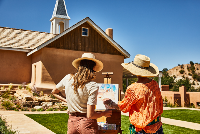 Two women paint a watercolor of Archbishop Lamy's Chapel.