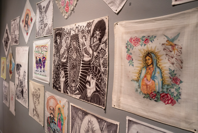 The paños are displayed to give the feeling of a family portrait wall in the exhibition "Between the Lines" at the Museum of International Folk Art in Santa Fe.