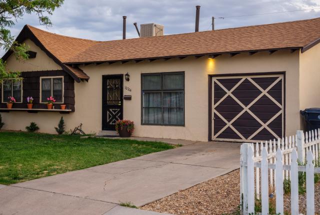 A well-kept Bellamah-style home with a crosshatched garage door and flower boxes under windows.