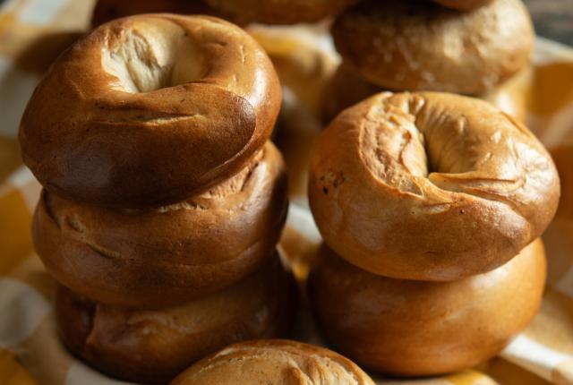 A variety of fresh-baked bagels are stacked on a cloth.