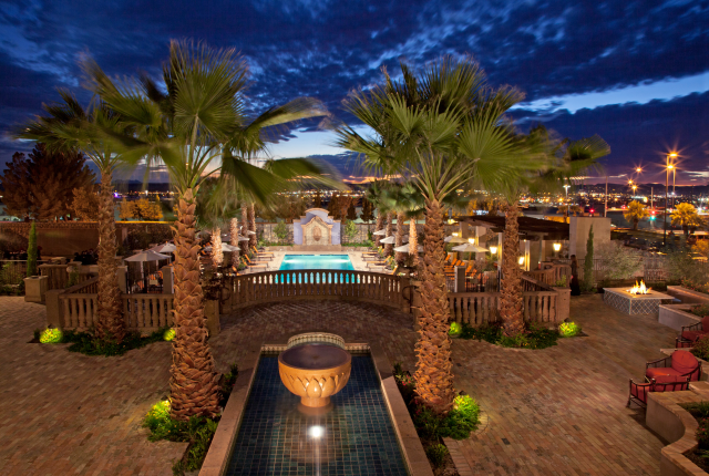 Palm-lined pool at Hotel Encanto de Las Cruces at night.