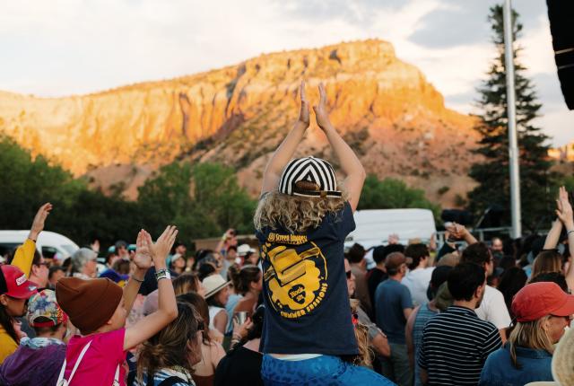 Festivalgoers raise their hands during a concert at Ghost Ranch's Blossoms & Bones music festival.