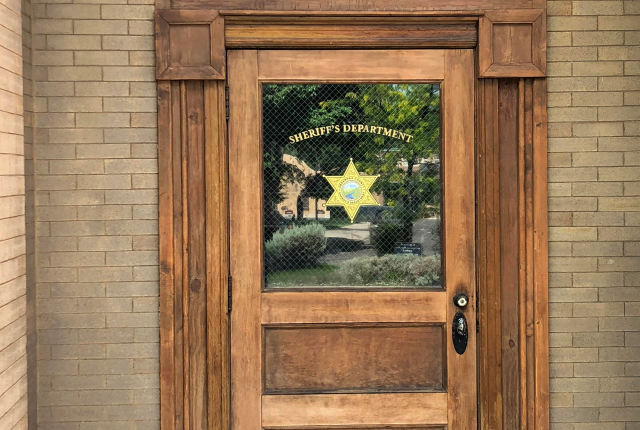 Wood and glass door marked "Sheriff's Department" at the historic filming location for Walt Longmire's fictional office in Las Vegas, New Mexico.