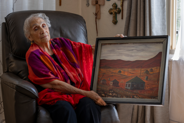 At her Albuquerque home, Petra Tovar Sánchez, born in Dawson in 1928, holds a painting of her former neighborhood.