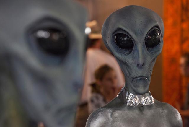 Close-up of two gray alien figures with large black eyes in a display setting.