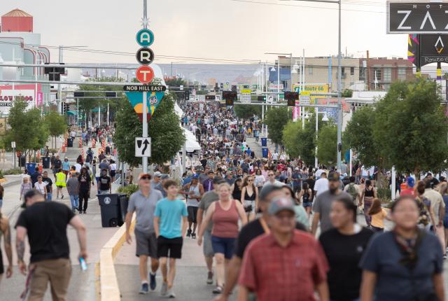 A large crowd of people walk down a city street.
