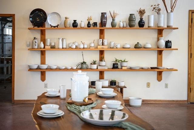 Sage Valley Pottery showroom with shelves of handmade ceramics and a table set with pottery dishes.