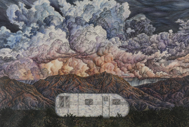 A silver trailer sits in front of a mountain range with dramatic, swirling clouds overhead.