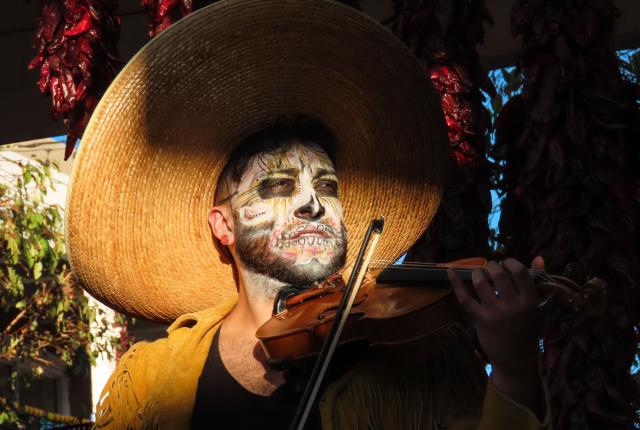 A mariachi musician plays violin in Old Town Albuquerque at sunset.
