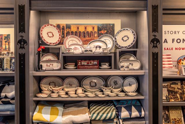 A display shelf with pottery, blankets, and books on southwestern themes.